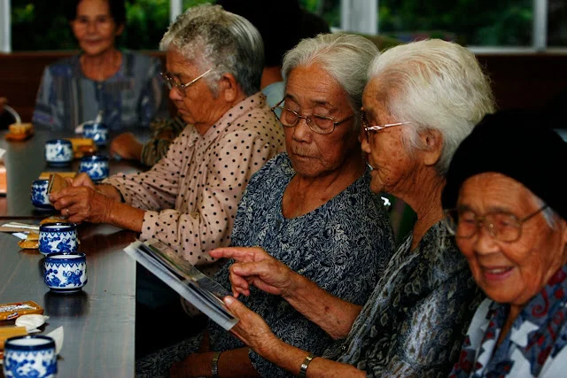 Personas ancianas de Okinawa reunidas alrededor de una mesa tomando té