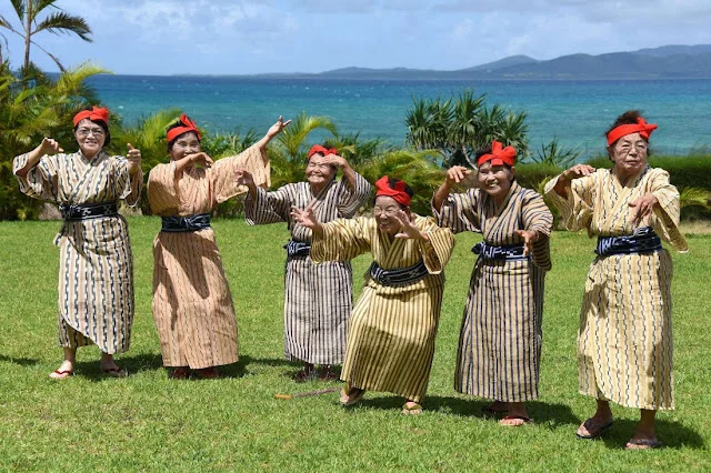 Mujeres mayores de Okinawa con kimono tradicional bailando juntas junto al mar