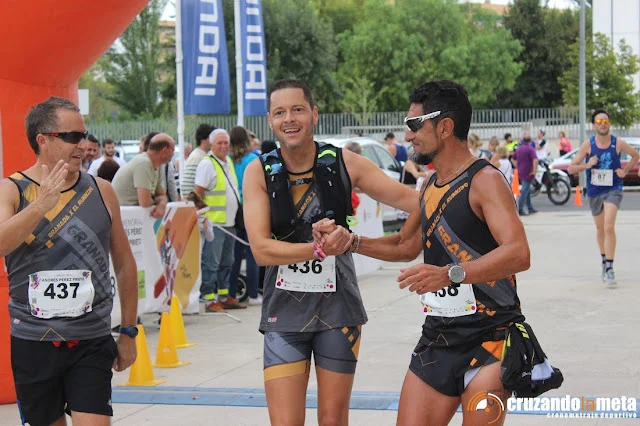Corredores cruzando la meta de una carrera, sonrientes y apoyándose entre ellos