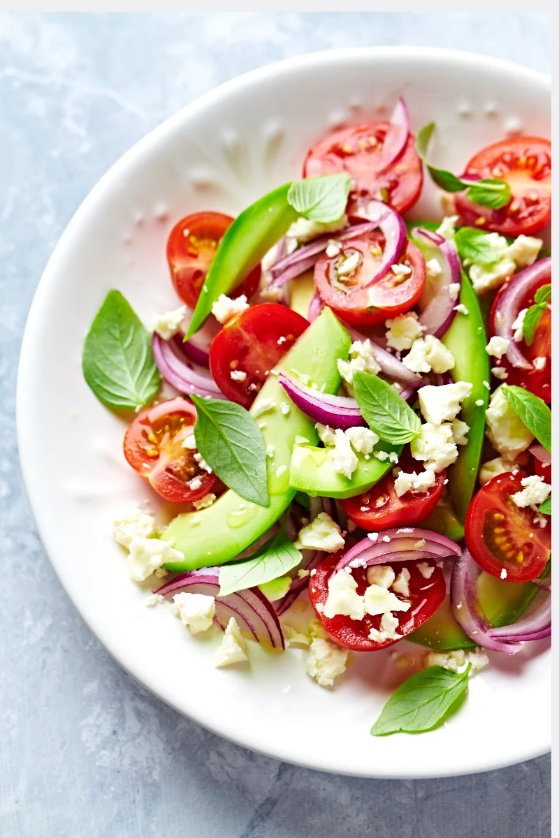 Ensalada anticáncer con tomates cherry, aguacate, cebolla morada, queso feta y albahaca fresca, apta para pacientes en quimioterapia