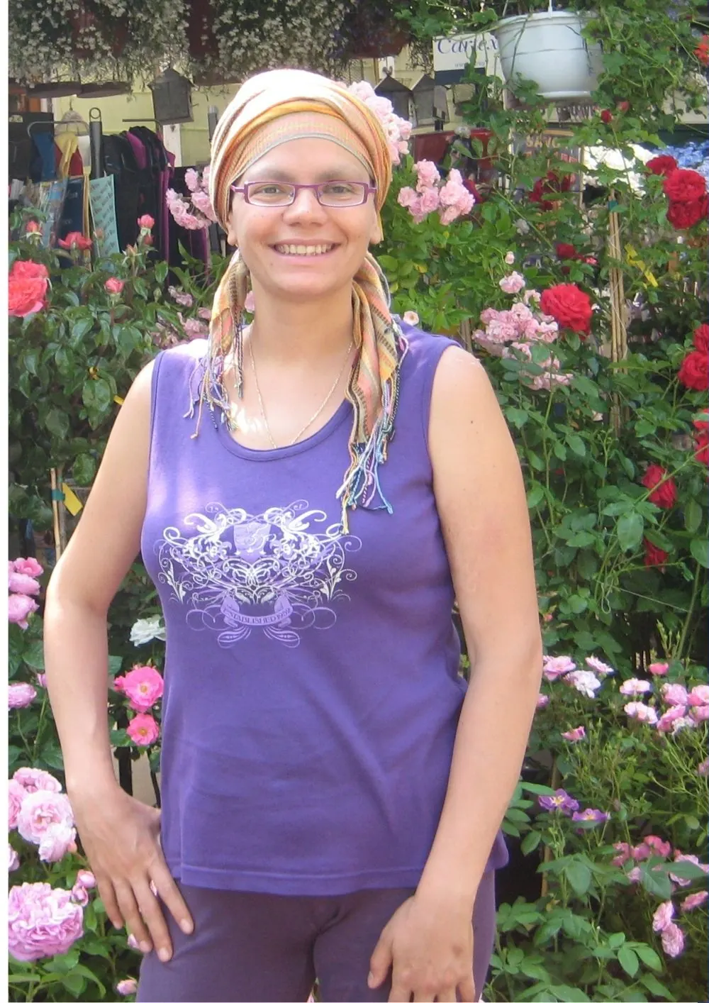 Odile Fernández en 2011, con pañuelo en la cabeza durante la quimioterapia, sonriendo en un jardín de rosas